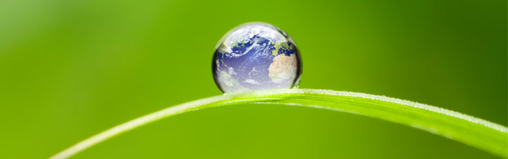 A water drop on the ground with a picture of earth in it.