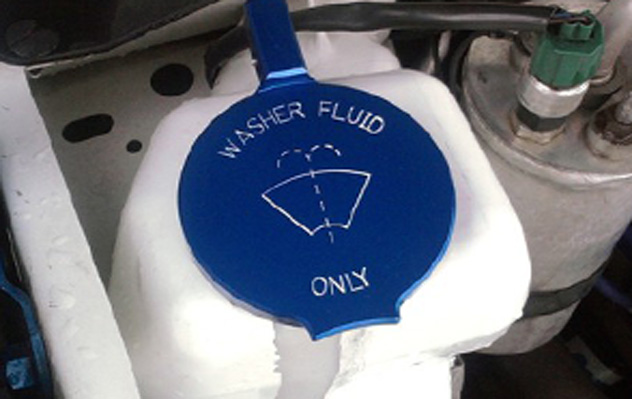 A blue washer fluid cap sitting on top of the engine.